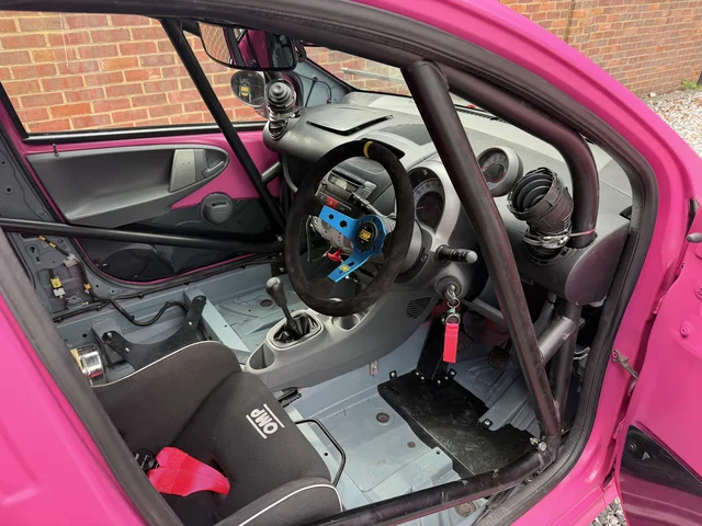 The actual race cockpit: OMP seat, harness, blue steering-wheel centre and controls